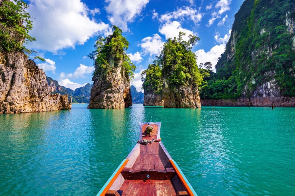 Dramatic limestone mountains and emerald waters of Ratchaprapha Dam in Khao Sok National Park, featured in a luxury Thailand travel blog by Amore Travel Designs.