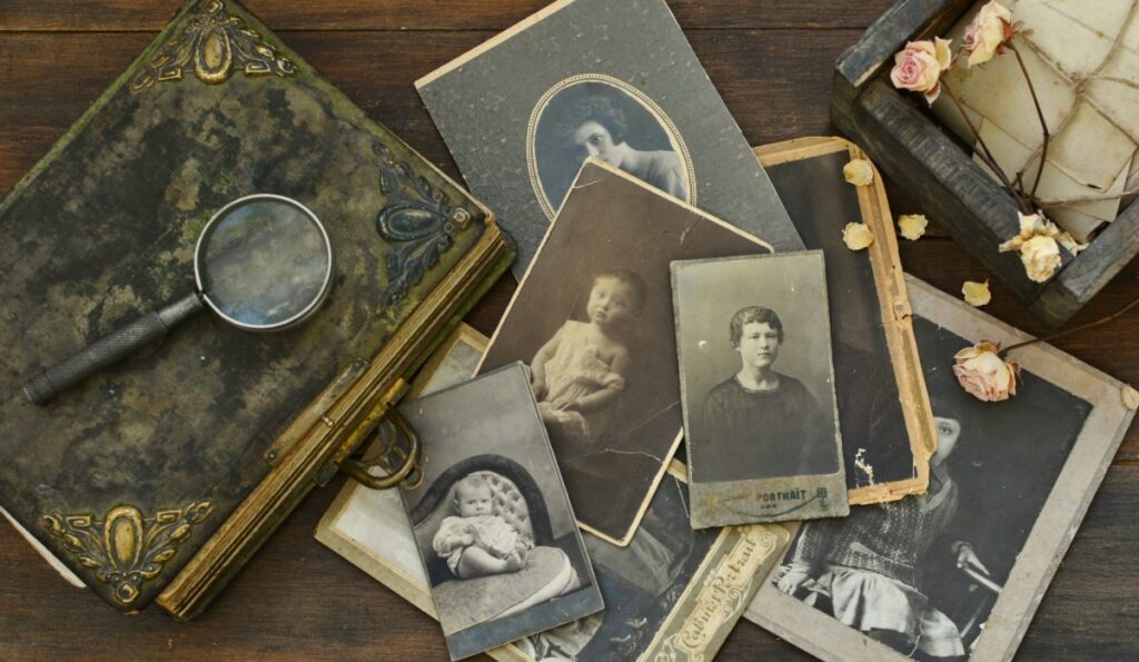Vintage family photographs, magnifying glass, and keepsakes symbolizing heritage travel research planned by Fort Collins luxury travel advisor Amore Travel Designs.