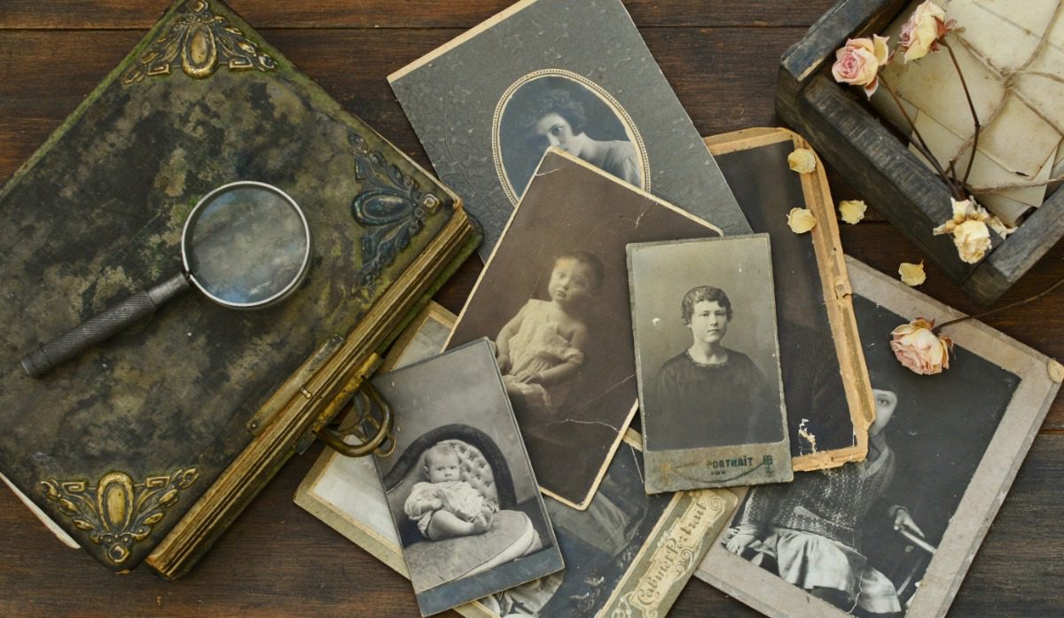 Vintage family photographs, magnifying glass, and keepsakes symbolizing heritage travel research planned by Fort Collins luxury travel advisor Amore Travel Designs.