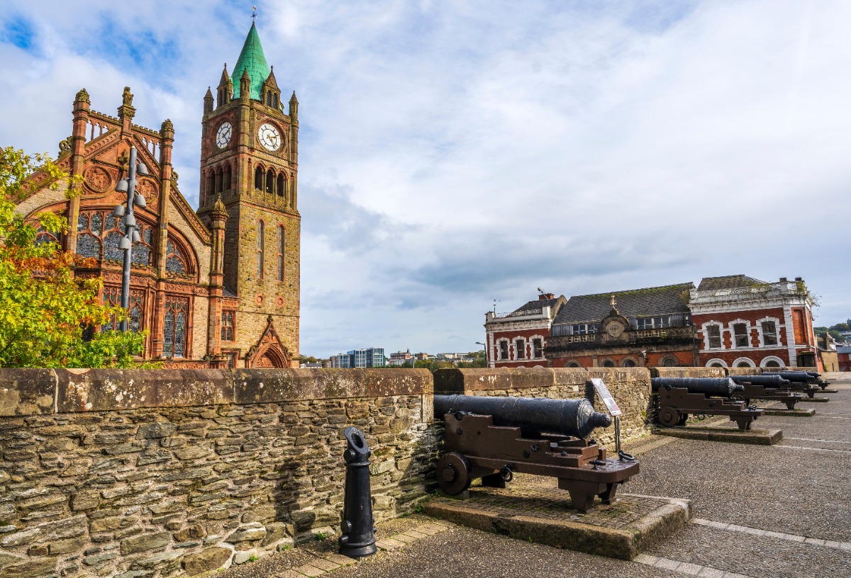 Historic Guildhall and cannons along Derry’s ancient city walls under soft Irish light — a blend of history and elegance captured for Ghostly Glamour Ireland, curated by Fort Collins luxury travel advisor Amore Travel Designs.