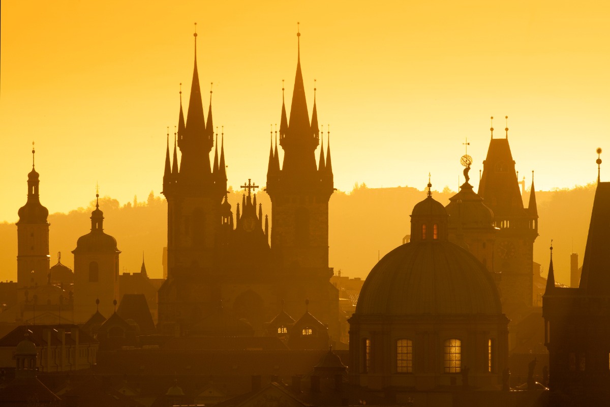 Golden sunrise over Prague’s Gothic skyline with spires and domes glowing in the morning mist — a romantic European cityscape captured by Amore Travel Designs, Fort Collins luxury travel advisor and Europe travel expert specializing in luxury haunted getaways.