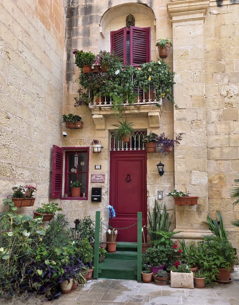 Colorful Maltese townhouse with flowers, balconies, and historic stone walls in Mdina, captured during a luxury cultural immersion trip.
