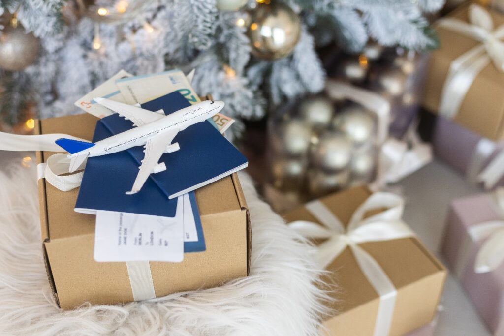 Luxury travel gift concept featuring passports, boarding passes, and a model airplane on wrapped presents, symbolizing meaningful experiences planned by a Fort Collins luxury travel advisor