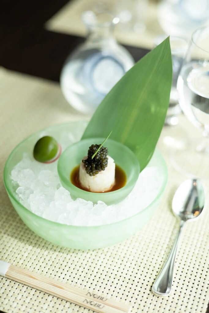 Elegant Nobu-style appetizer featuring chilled seafood topped with caviar, artfully plated onboard Crystal Serenity, highlighting the refined luxury dining experience curated by Amore Travel Designs, Fort Collins’ luxury travel advisor.