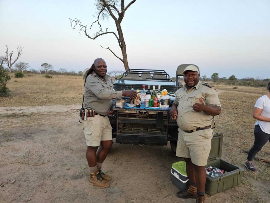 Safari guides setting up sundowner drinks beside a game vehicle in South Africa’s Sabi Sand Game Reserve during a luxury African safari experience.