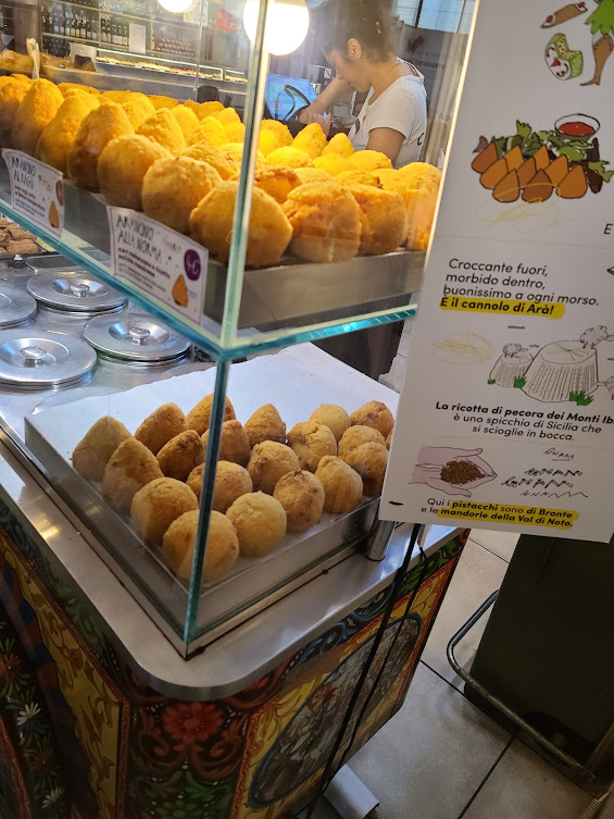 Fresh Sicilian arancini displayed at a food stall inside Florence’s Mercato Centrale, a popular spot for authentic Italian street food and local specialties.