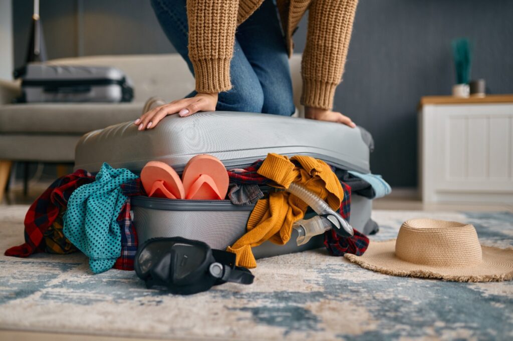 Overpacked suitcase bursting with clothes and travel gear — a luxury travel advisor shares smarter packing tips for a European trip with Amore Travel Designs.