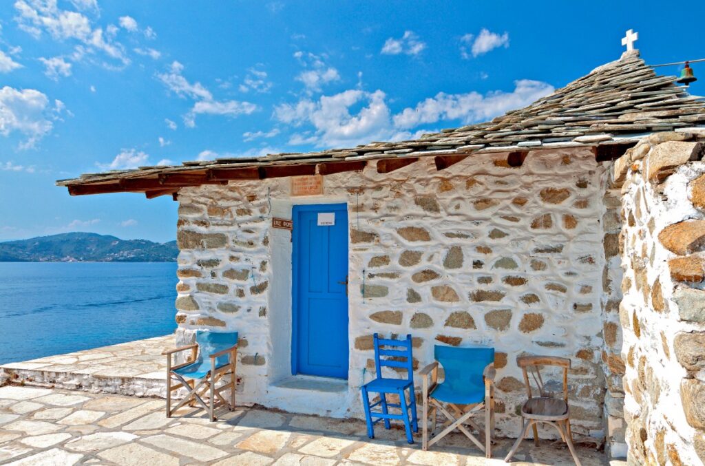 A whitewashed chapel, a blue door, and the Aegean stretching to forever — this is exactly what Mamma Mia promised, and exactly what Skiathos delivers